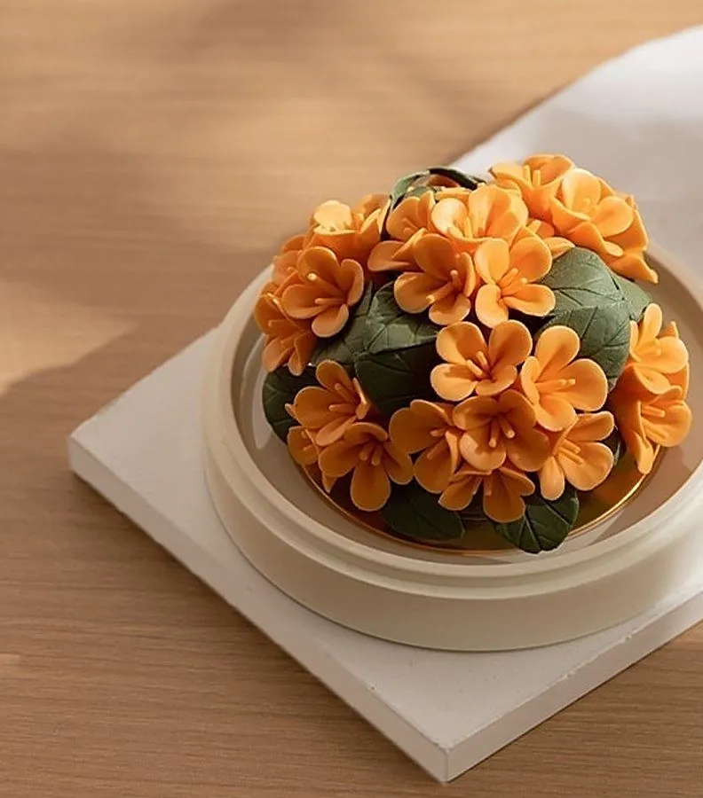 A porcelain osmanthus flower on a white stand